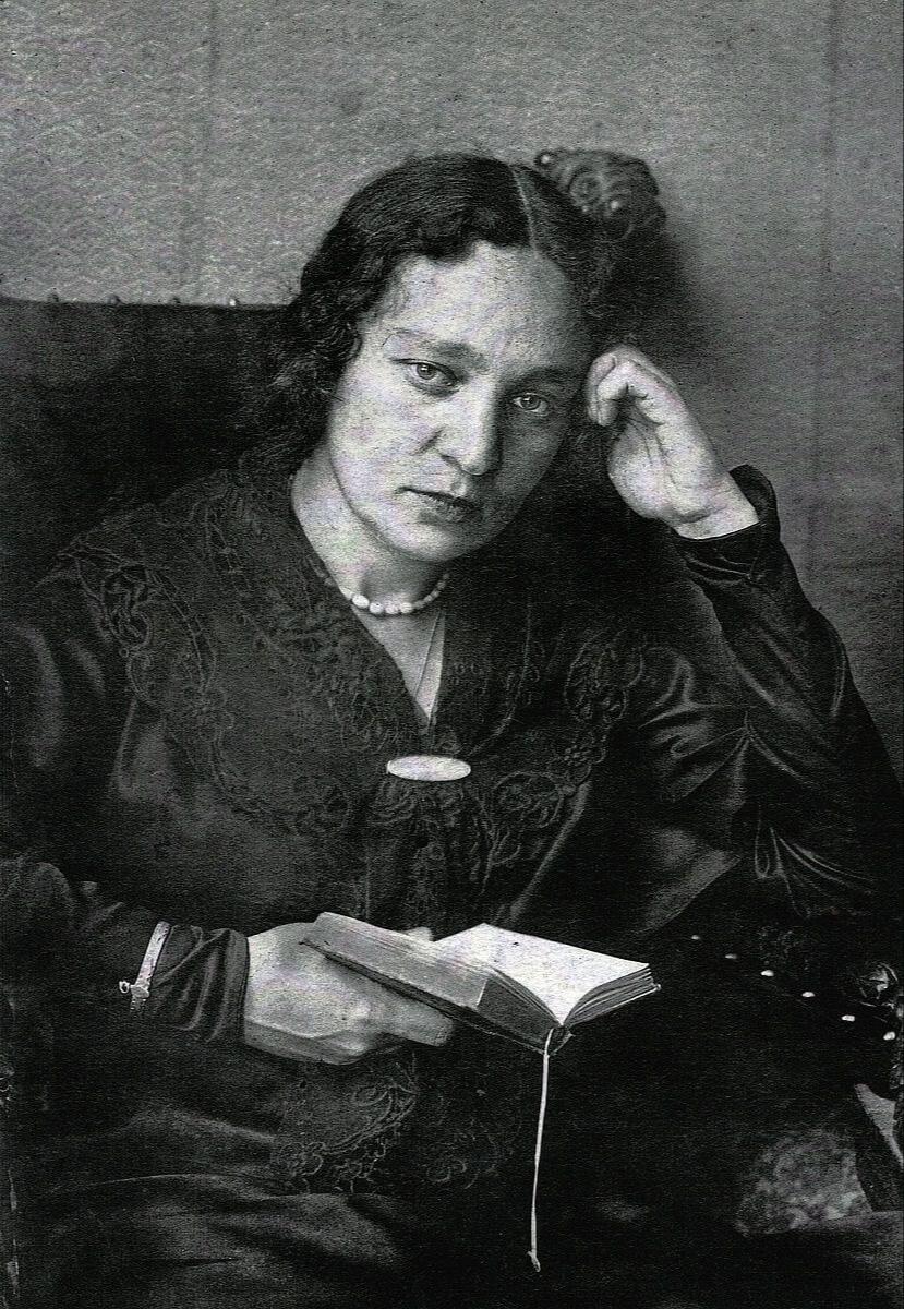 Портрет М. В. Юдиной. Мария сидит в кружевном платье, держит в руках книгу.